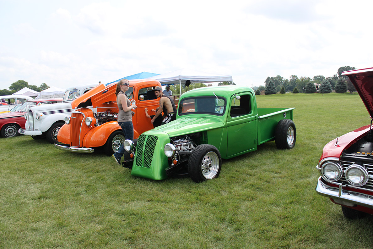 Green and orange trucks at car show
