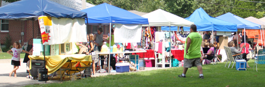 A row of canopies where vendors sell goods to patrons at the festival.